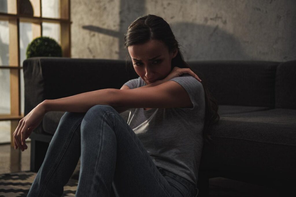 Woman sits on floor as she begins to struggle with some severe meth side effects