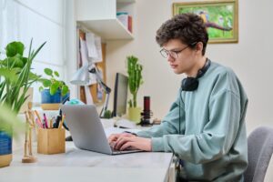 Teen sits at his laptop and looks up benefits to drug and alcohol couseling online