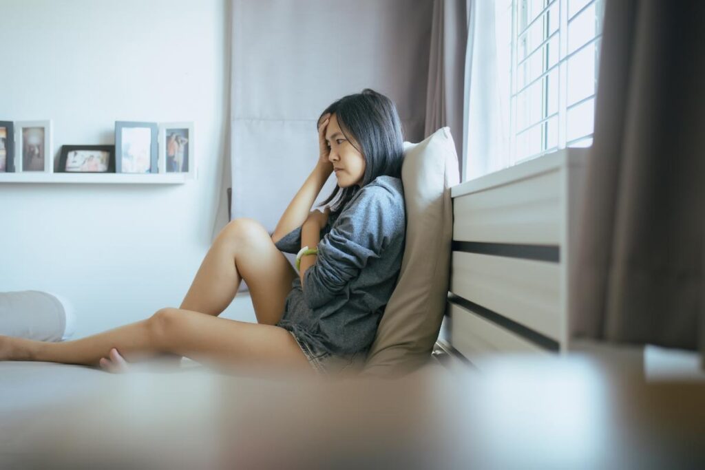 Woman sits on bed and wonders if alcohol makes her sleepy