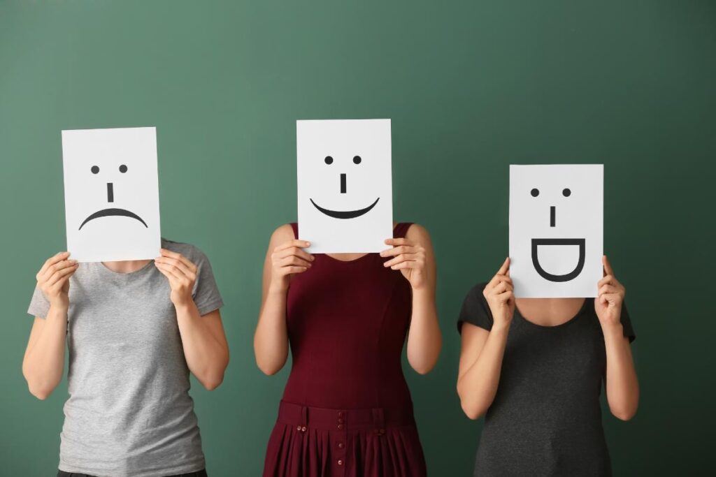 People holding up smile and frown faces to symbolize the difference between bipolar 1 vs 2