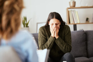 Woman on couch begins to break down after therapist explains the importance of caring for your mental health